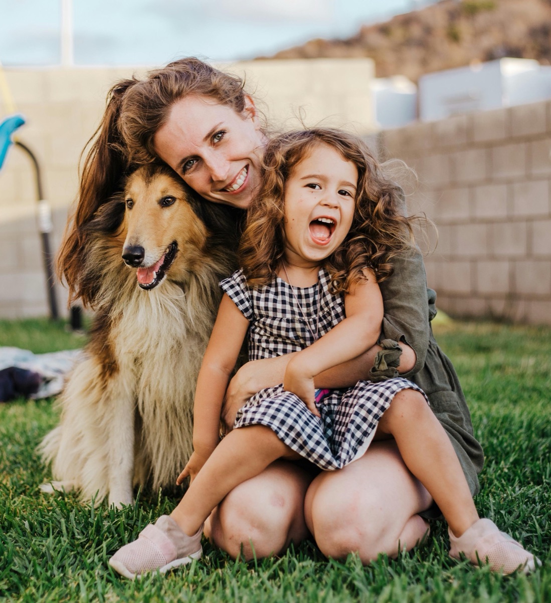 A mother, her daughter, and their dog on the lawn